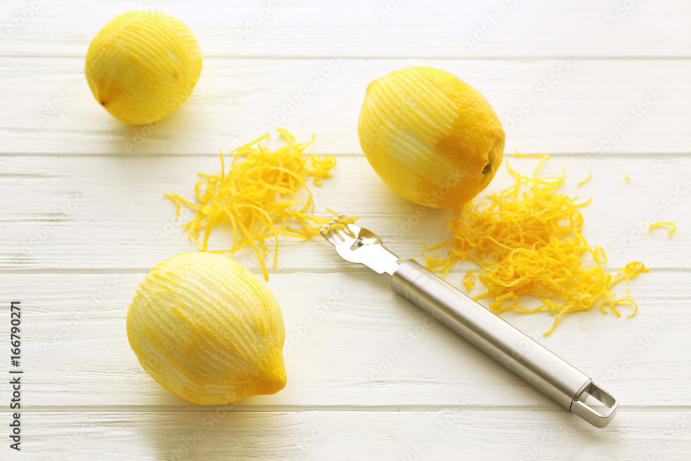 Wall mural Fresh peeled lemons, special tool and zest on wooden table