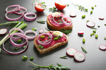 Delicious spicy toasts with onion and egg on dark table