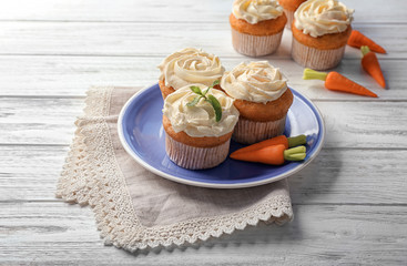 Plate with delicious carrot muffins on wooden table