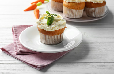Plate with delicious carrot muffin on wooden table