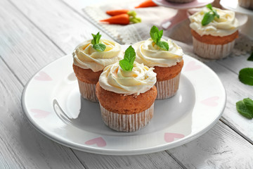 Plate with delicious carrot muffins on wooden table