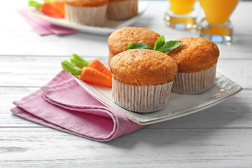 Plate with delicious carrot muffins on wooden table