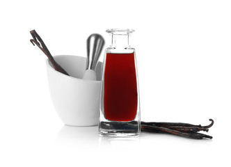 Bottle with vanilla extract, sticks and mortar on white background