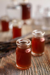 Bottle with vanilla extract on wooden table