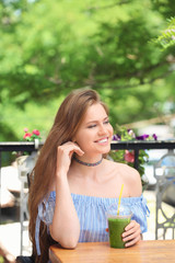 Lively young woman drinking fresh smoothie in cafe