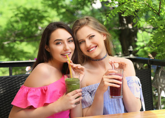 Two attractive ladies enjoying fresh smoothie in cafe