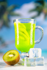 Tasty drink with kiwi on sandy beach
