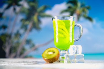 Tasty drink with kiwi on sandy beach