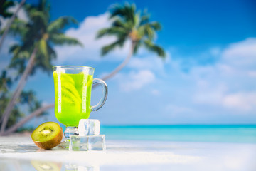 Tasty drink with kiwi on sandy beach