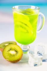 Tasty drink with kiwi on sandy beach