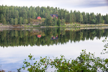 Red house and forest reflecting in lake