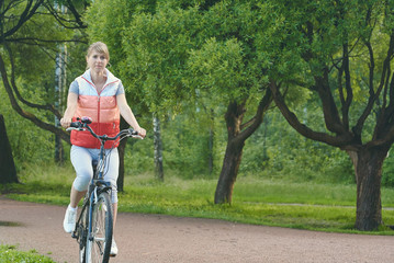 Obraz premium Young girl riding a bike in a park. She is moving towards the camera.