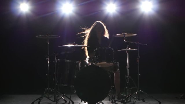 Drummer comes off at a rock concert. Black smoke background. Silhouette