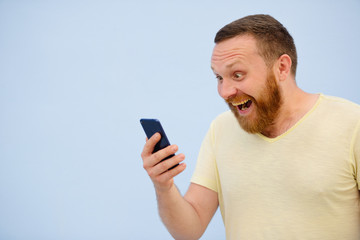 Bearded Man looking into the phone rejoices photo to advertise a lot of space under the text