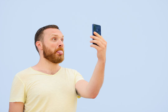 man makes faces in a funny and humorous phone shows a language, an advertising company