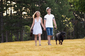 Young couple in love with guitar and dog rottweiler in the nature