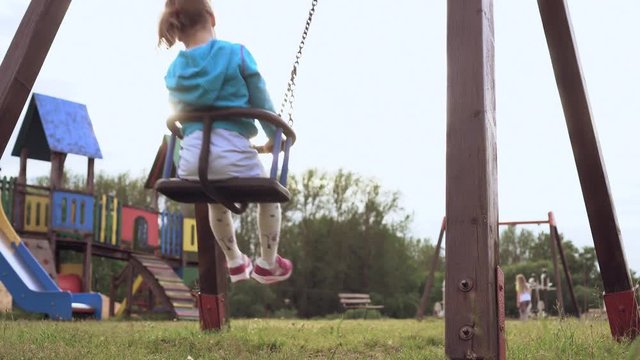 Father pushing child on a swing set. Two girls are swaying opp. each other. Slow Motion