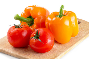 Orange pepper and tomatoes on a cutting board on isolated background