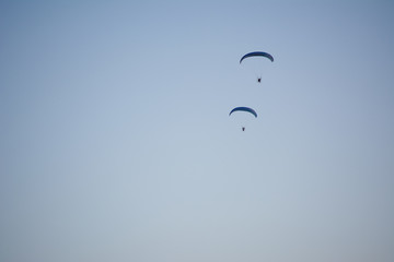 Silhouette of a male paraglider on a paraplan against a background of a sunset in the sky and clouds hovering over the sea. Concept: freedom, loneliness, hobby, sport.