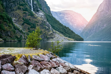 Fototapeta premium Golden sunrise in the mountains, Gudvangen Norway with reflection in the water of the fjord.