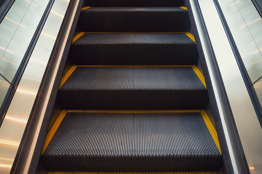 Empty escalator or moving stair. Also called stairway or staircase. Modern architecture design with step, glass for lift people up floor building i.e. shopping mall, airport, metro and subway station.