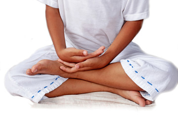 The boy in white dress is meditating on white background.