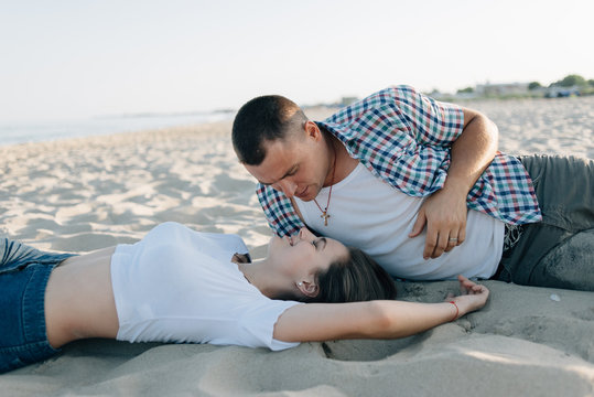 The guy and the girl lie on sand