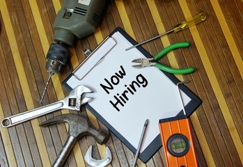 Construction work concept. Notepad and various tools with word  now hiring
