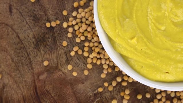Portion of Mustard rotating on a wooden plate (not loopale; 4K)