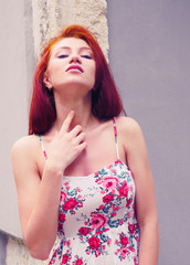 Fototapeta premium Red hair girl in mini dress and hat posing in front of camera. Pretty girl looking at camera and smiling. Happy hipster ginger girl portrait. Cute girl with red hair on the street. 