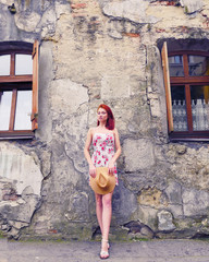 Red hair girl in mini dress and hat posing in front of camera. Pretty girl looking at camera and...