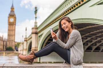 London urban people city lifestyle woman using phone app texting sms on social media. Young Asian...