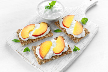 Homemade Crispbread toast with Cottage Cheese and nectarine on white wooden board.