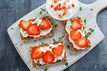Homemade Crispbread toast with Cottage Cheese and Strawberry on white wooden board.