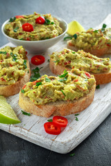 Homemade Guacamole toast with chili pepper, parsley on white wooden board