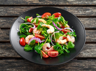 Fresh Healthy Prawns salad with tomatoes, red onion on black plate. concept healthy food