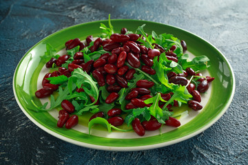 Red beans and wild rocket healthy salad in a green plate