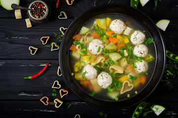 Chicken and vegetable soup with meatballs, zucchini and pasta. Flat lay. Top view
