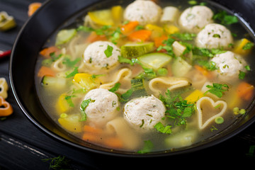 Chicken and vegetable soup with meatballs, zucchini and pasta.