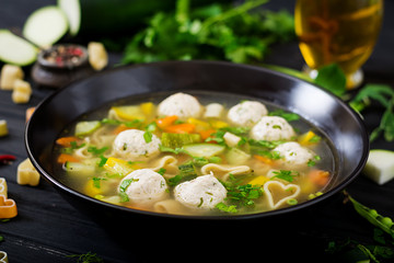 Chicken and vegetable soup with meatballs, zucchini and pasta.