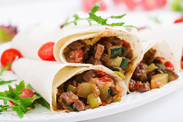 Burritos wraps with beef and vegetables on a light  background.