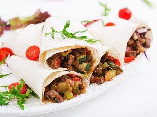 Burritos wraps with beef and vegetables on a light  background.