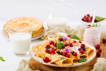 Pancakes with yoghurt, honey, nuts and summer berries. Tasty breakfast.