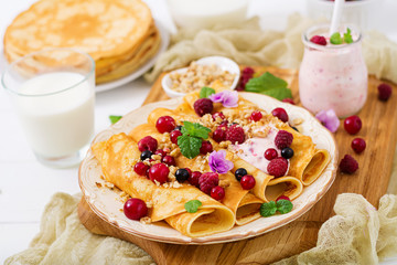 Pancakes with yoghurt, honey, nuts and summer berries. Tasty breakfast.