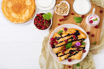 Pancakes with chocolate, honey, nuts and summer berries. Tasty breakfast.  Flat lay. Top view