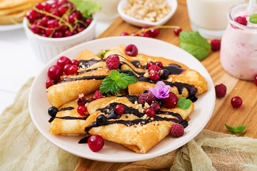Pancakes with chocolate, honey, nuts and summer berries. Tasty breakfast