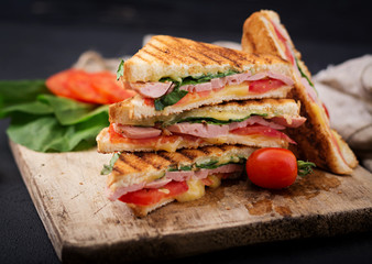 Club sandwich panini with ham, tomato, cheese and basil.