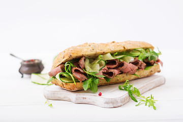 Sandwich of whole wheat bread with roast beef, cucumber and arugula.
