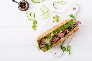 Sandwich of whole wheat bread with roast beef, cucumber and arugula. Top view. Flat lay