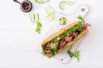  Sandwich of whole wheat bread with roast beef, cucumber and arugula. Top view. Flat lay © timolina